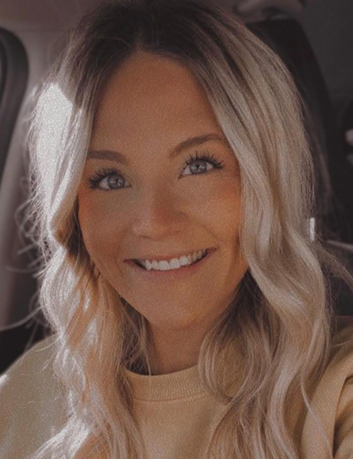 A barber and a smiling child, possibly at a salon, with the child in a cape and the barber wearing a hat.
