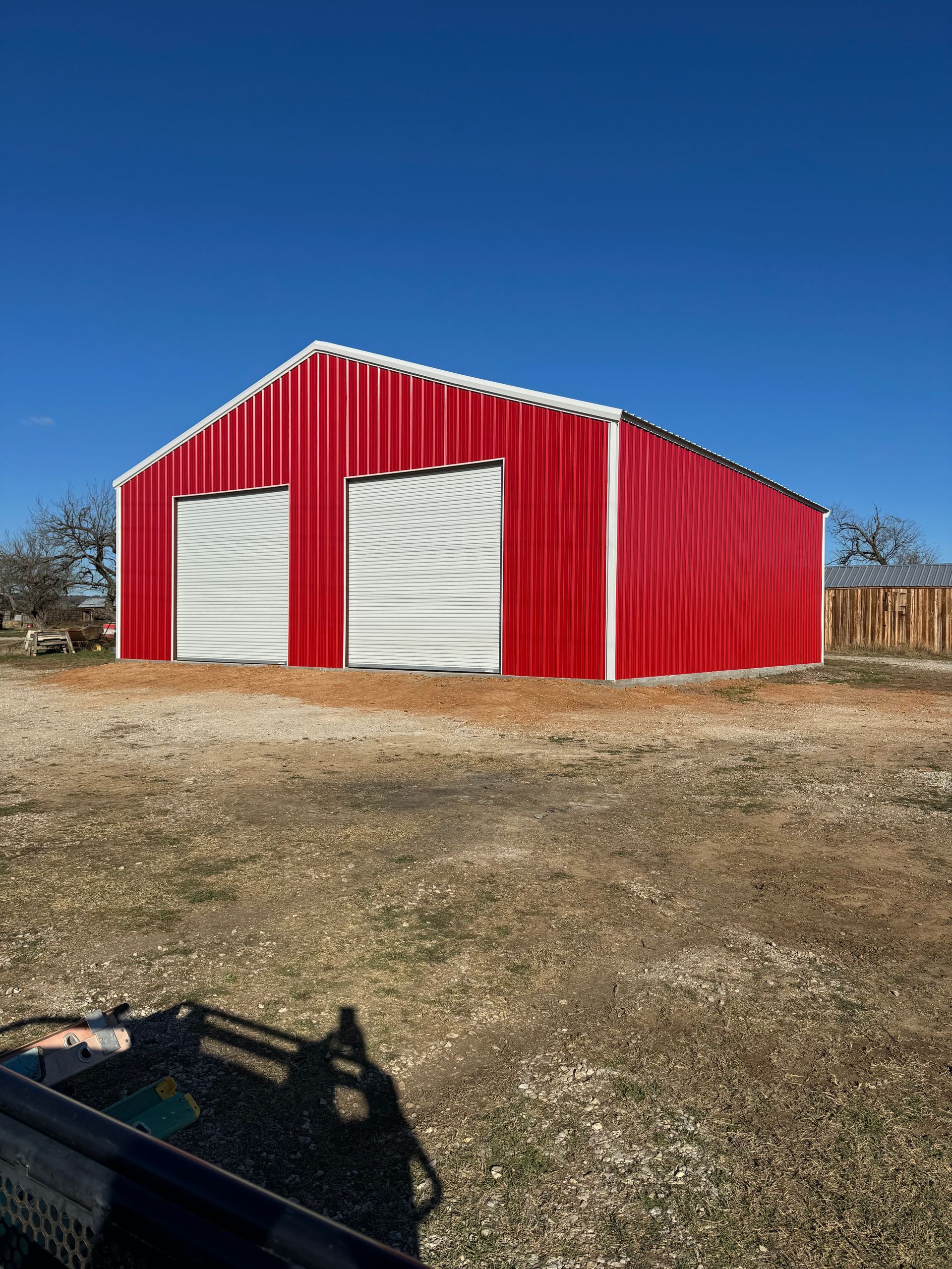 A red and white barn is sitting in the middle of a dirt field.