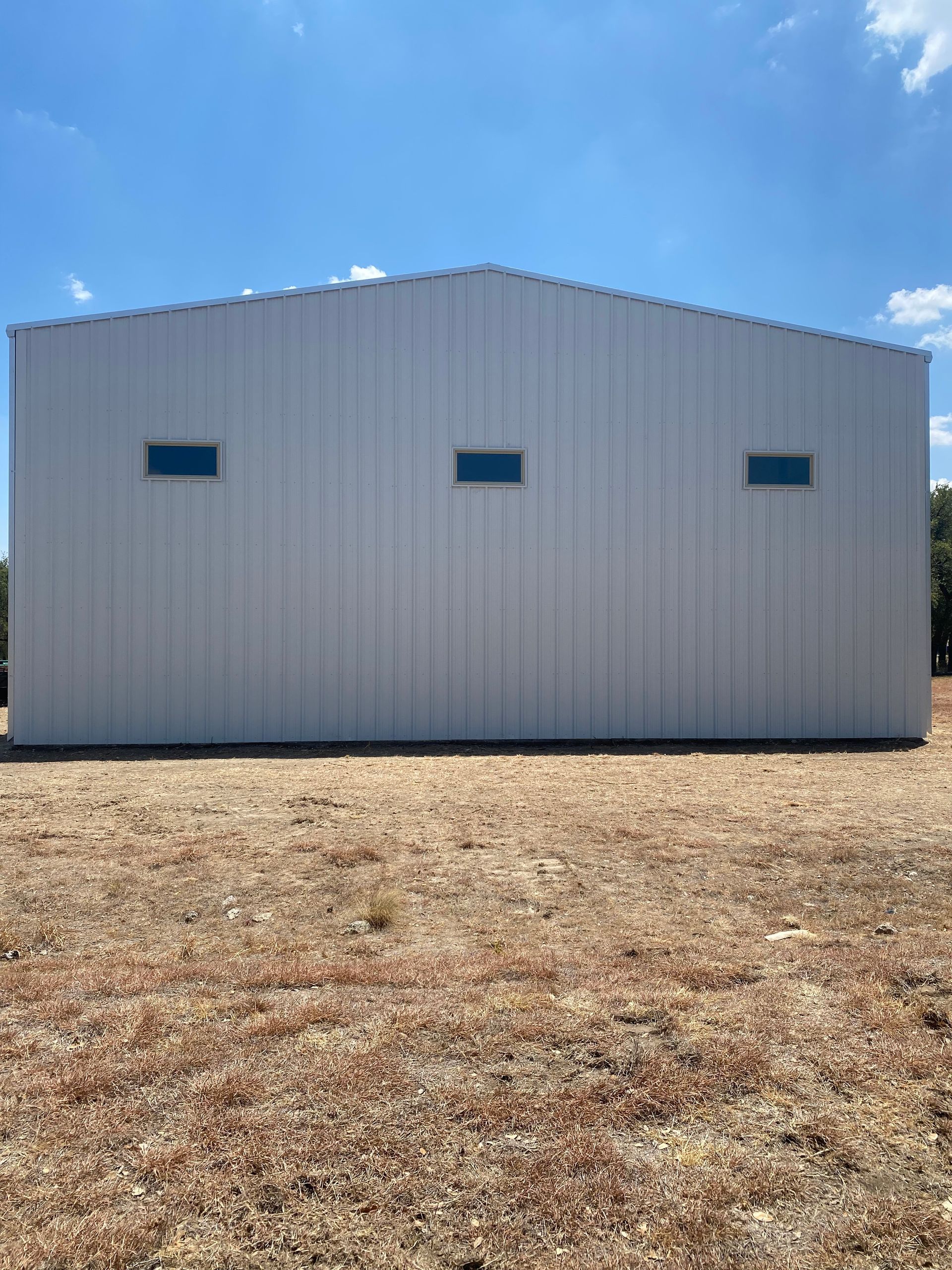 A large white building is sitting in the middle of a field.
