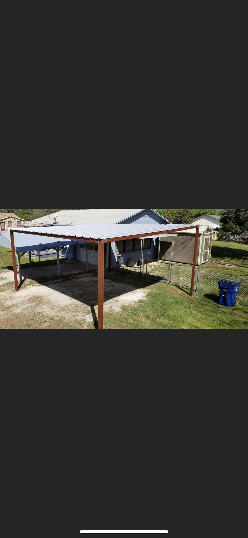 A metal garage with a canopy and a forklift parked in front of it.