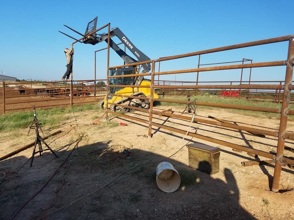 A man is working on a metal fence in a field