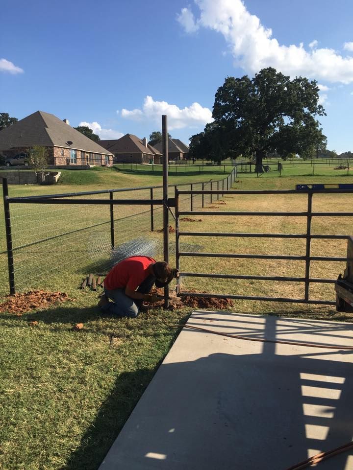 A man in a red shirt is working on a fence