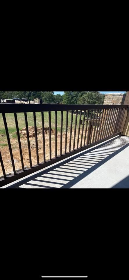A close up of a metal railing on a balcony with a field in the background.