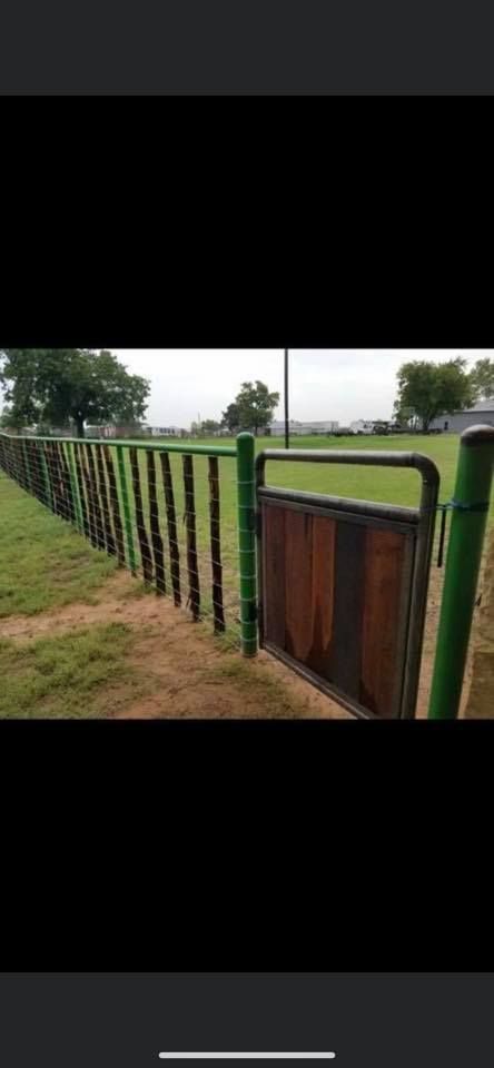 A fence with a gate in the middle of a field.