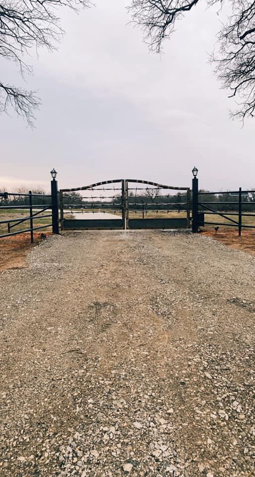 There is a gate in the middle of a gravel road.