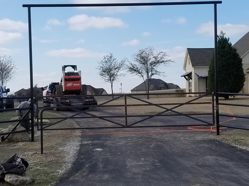A bulldozer is parked in front of a gate in a driveway.