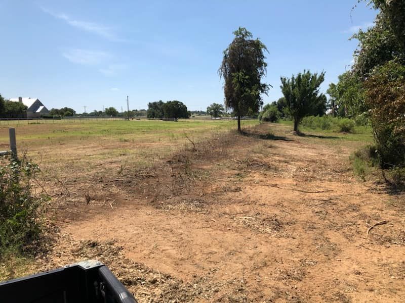 A truck is parked in the back of a dirt field.
