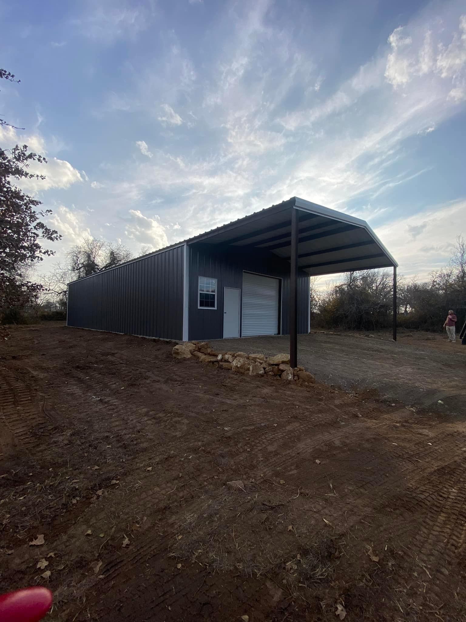 A metal building with a canopy over it is sitting on top of a dirt hill.
