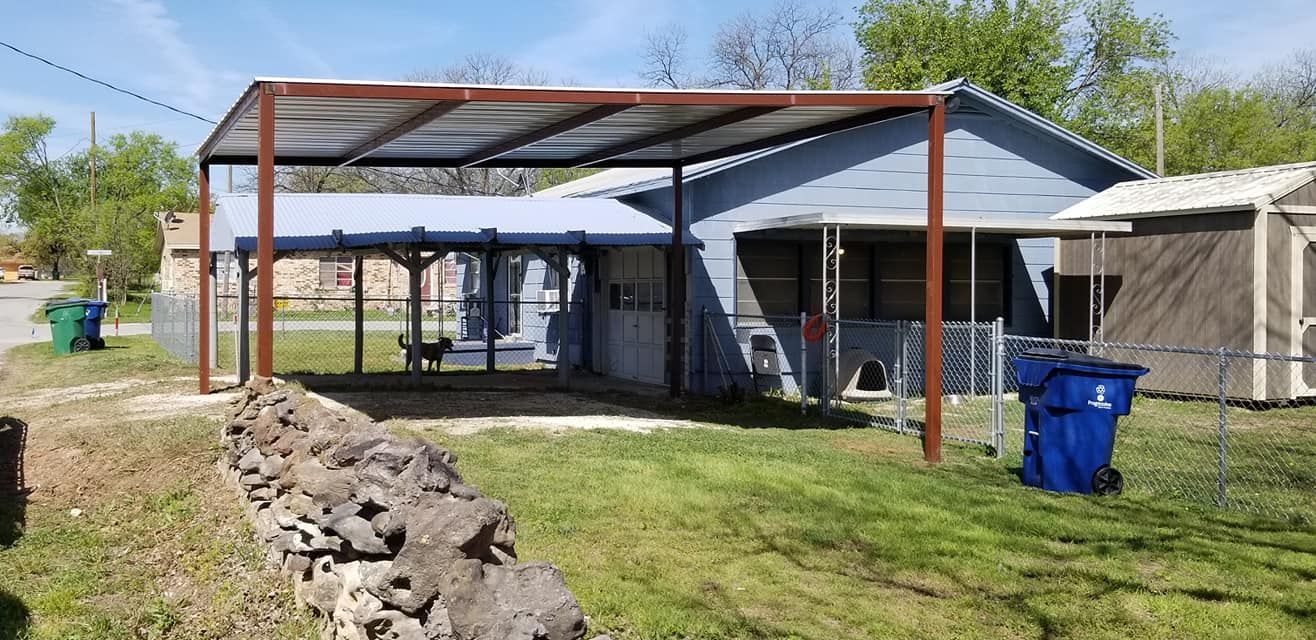 A house with a carport and trash cans in front of it.