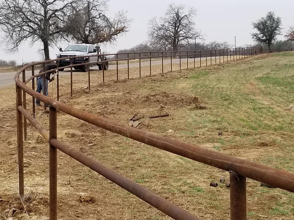 A truck is parked behind a rusty fence in a field