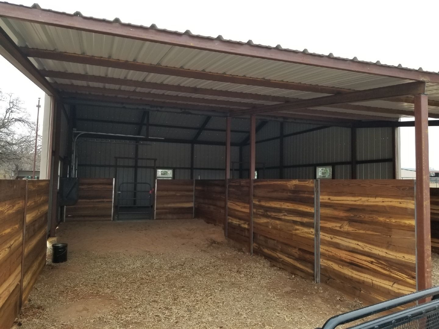 A horse stable with a wooden fence and a metal roof