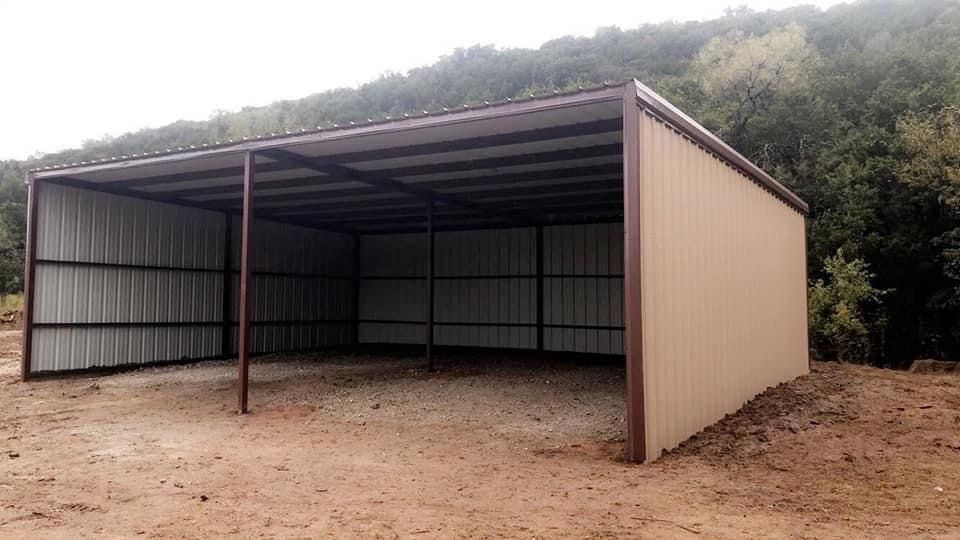 A large metal building is sitting in the middle of a dirt field.