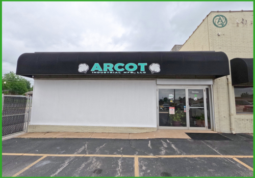 A low-angle view of the Arcot Industrial Mfg. LLC building with a black awning and glass entrance door.