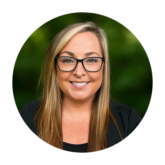 Woman with blonde hair, glasses, and a black blazer smiles, set against a blurred green background.