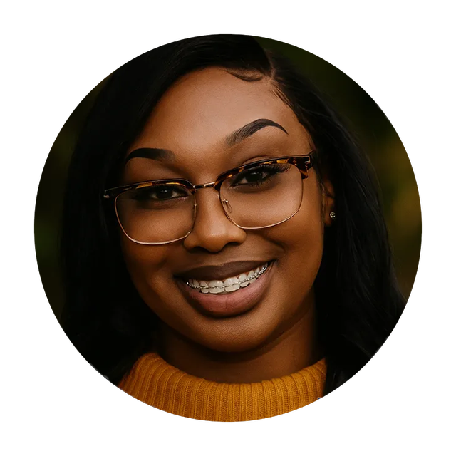 Woman with glasses and braces smiling, wearing a yellow sweater.