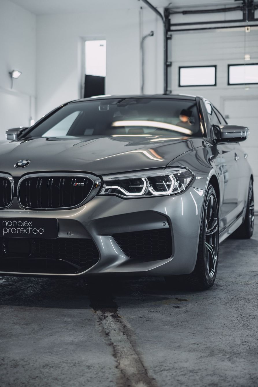 A bmw m5 is parked in a garage next to a garage door.