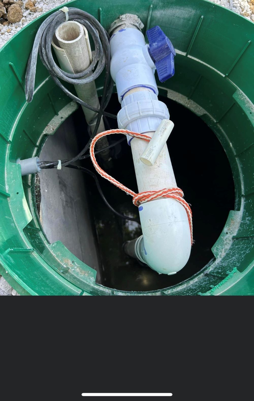 Green septic tank with white PVC pipes, wires, and copper rope inside.