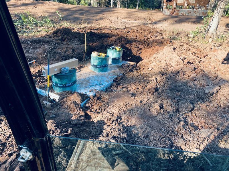 Construction site with green tanks and excavation in progress; a dirt setting.
