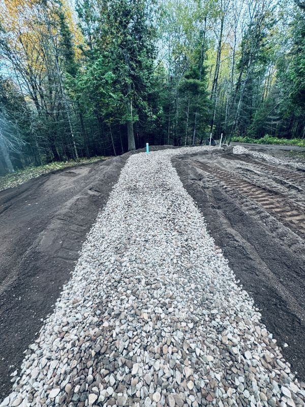 Gravel pathway through dirt, surrounded by trees in a wooded setting.