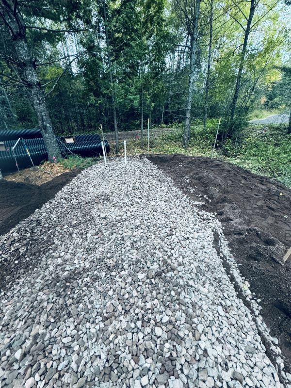 A gravel path under construction next to bare earth with trees in the background.