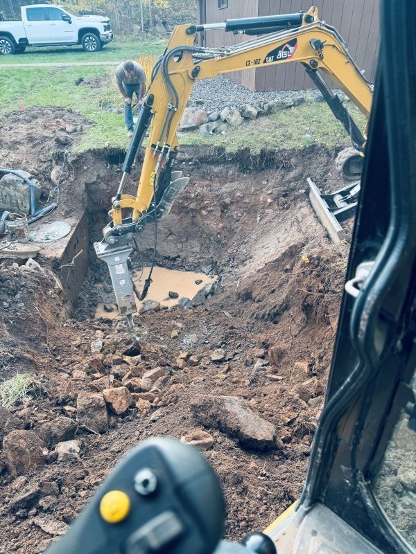 Yellow excavator digging in a construction site. A person is working.