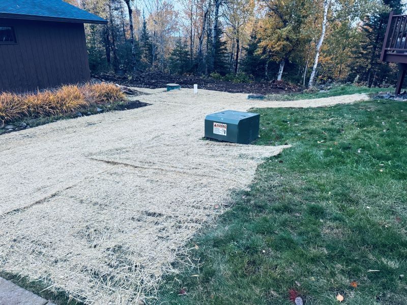 Gravel path leading from a building, next to green grass. A utility box sits on the gravel path.