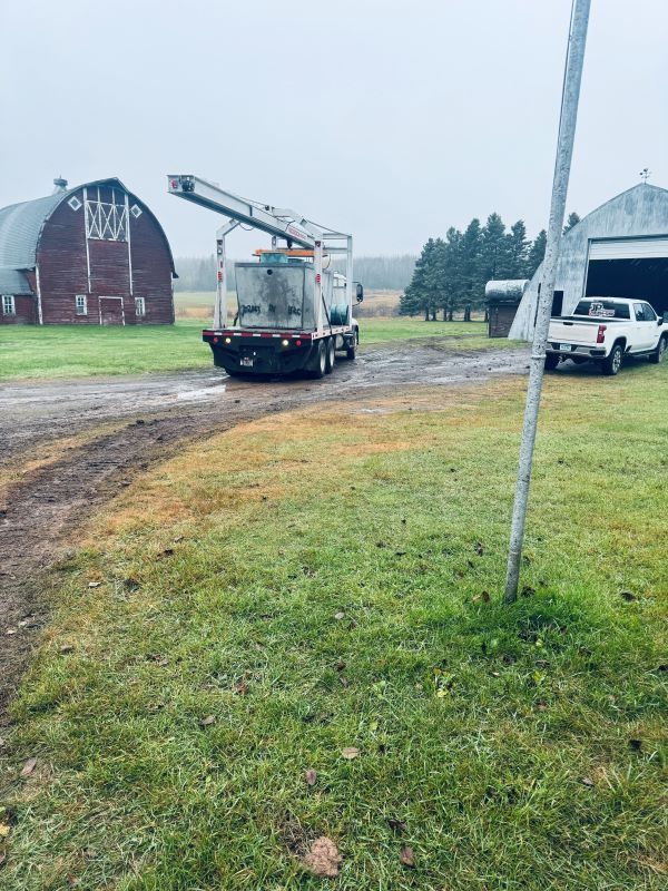 Truck on a farm; a red barn and white truck are in the background, overcast sky.