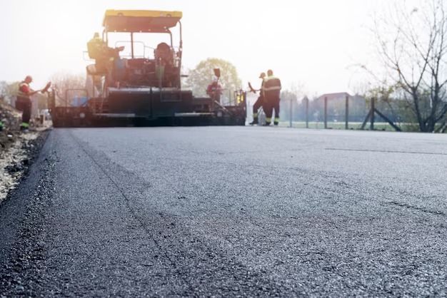 Asphalt road paving in progress; workers and machinery.