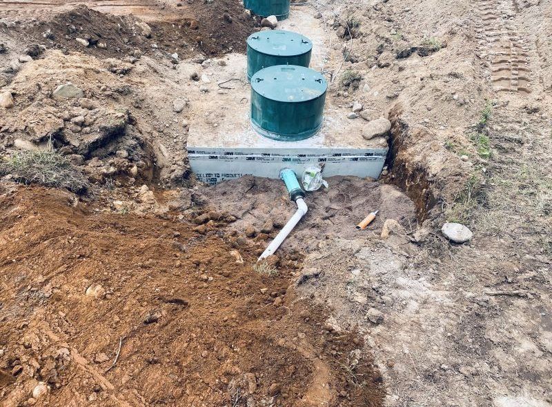 Septic system components exposed during installation: tanks, pipes, and a concrete base.