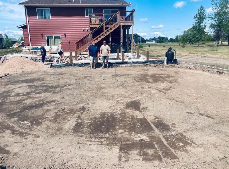People working on a construction site with a house in the background.