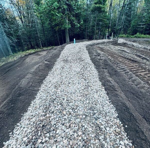 Gravel pathway winding through dirt, with trees in background.