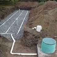 Septic system installation: Gravel leach field, PVC pipes, and a green septic tank.