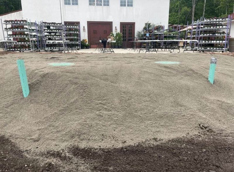 A sandy area with a building in the background, some racks on the sides, and green markers.