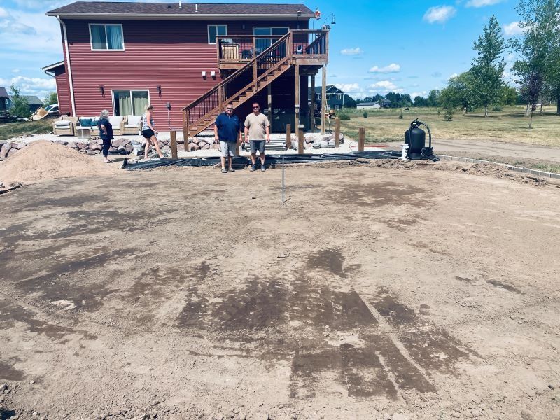 People standing on a dirt patch, likely a yard, near a two-story house.