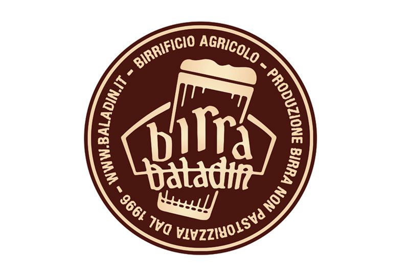 Logo del birrificio Birra Baladin con testo e bicchiere da birra, marrone e beige, dal 1998.
