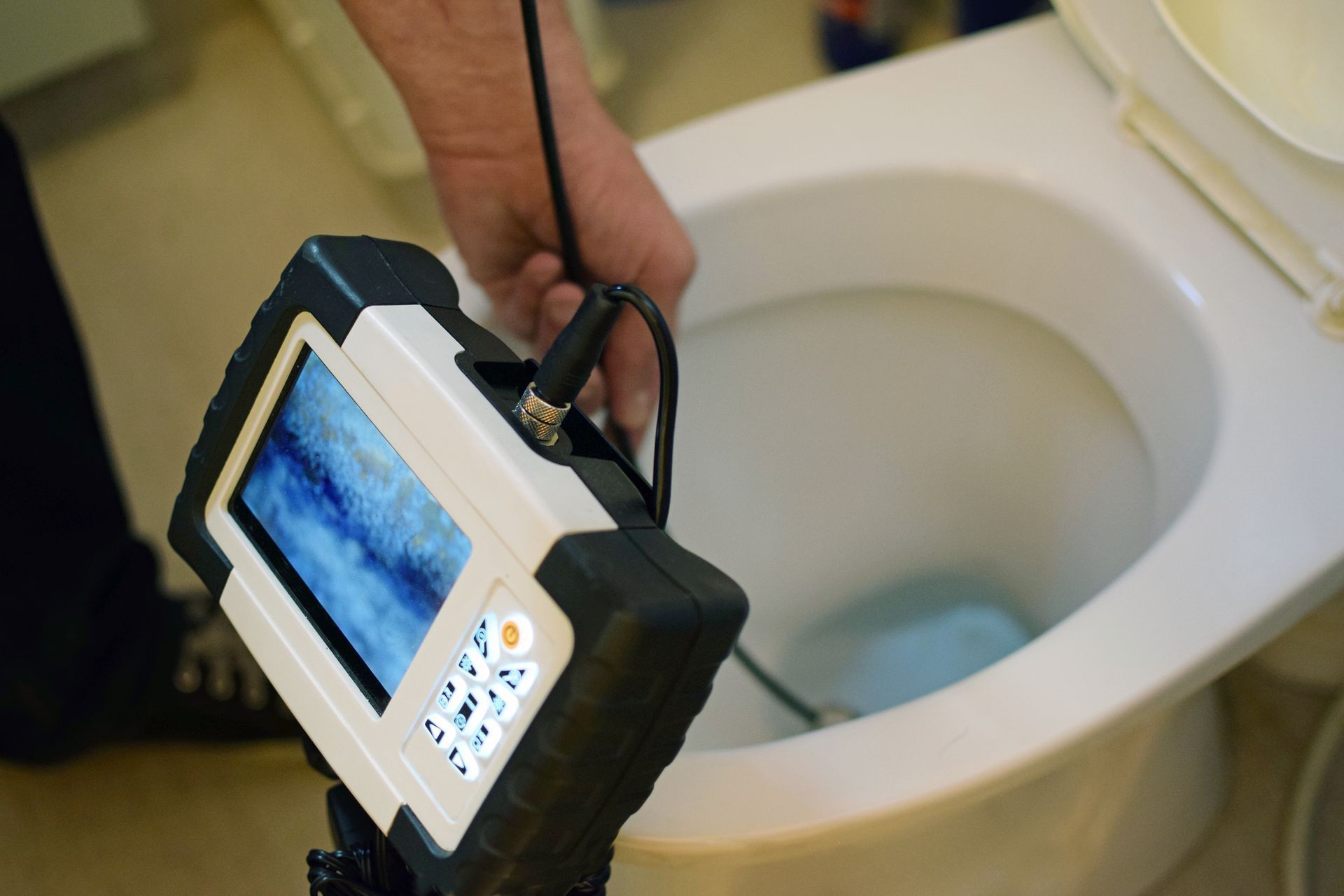 Une personne tient un appareil photo au-dessus des toilettes.