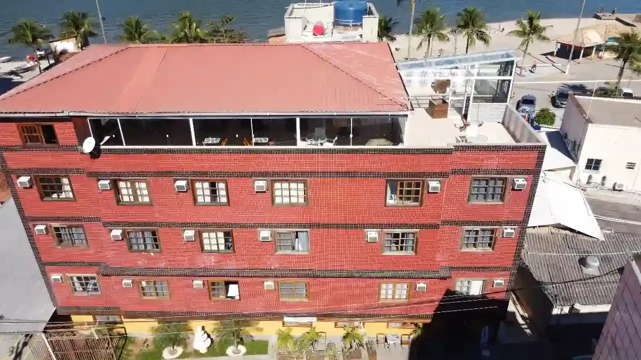 Uma vista aérea de um grande edifício vermelho próximo a um corpo d'água.-pousada-itacuruca-inn