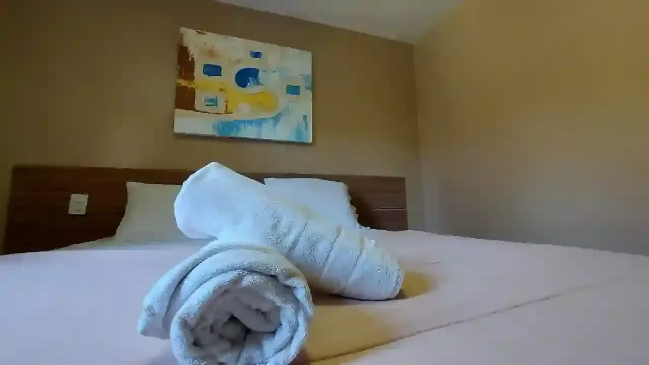 Duas toalhas estão enroladas em uma cama em um quarto de hotel.-pousada-itacuruca-inn