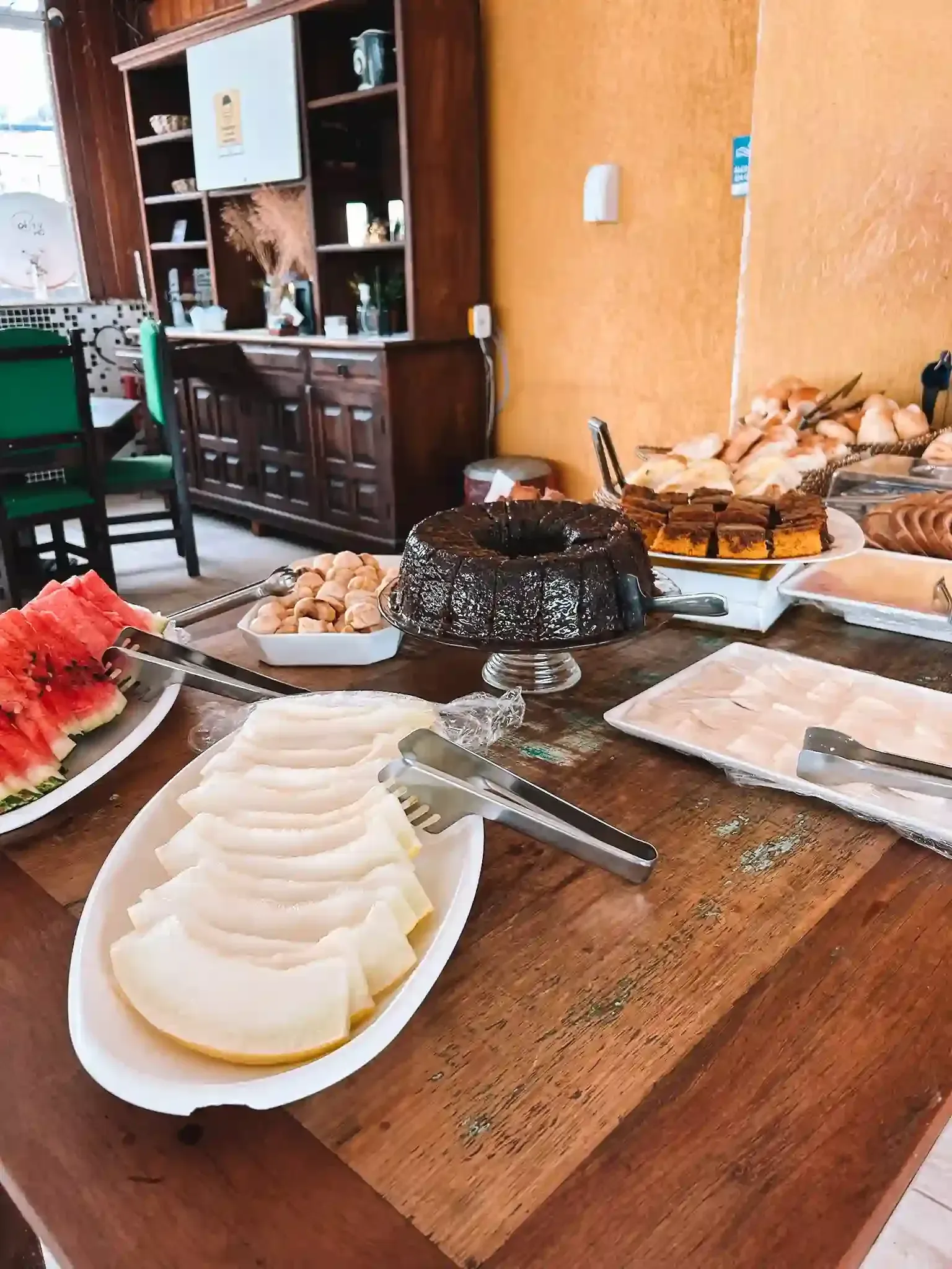 Uma mesa de madeira coberta com pratos de comida e um bolo.-pousada-itacuruca-inn