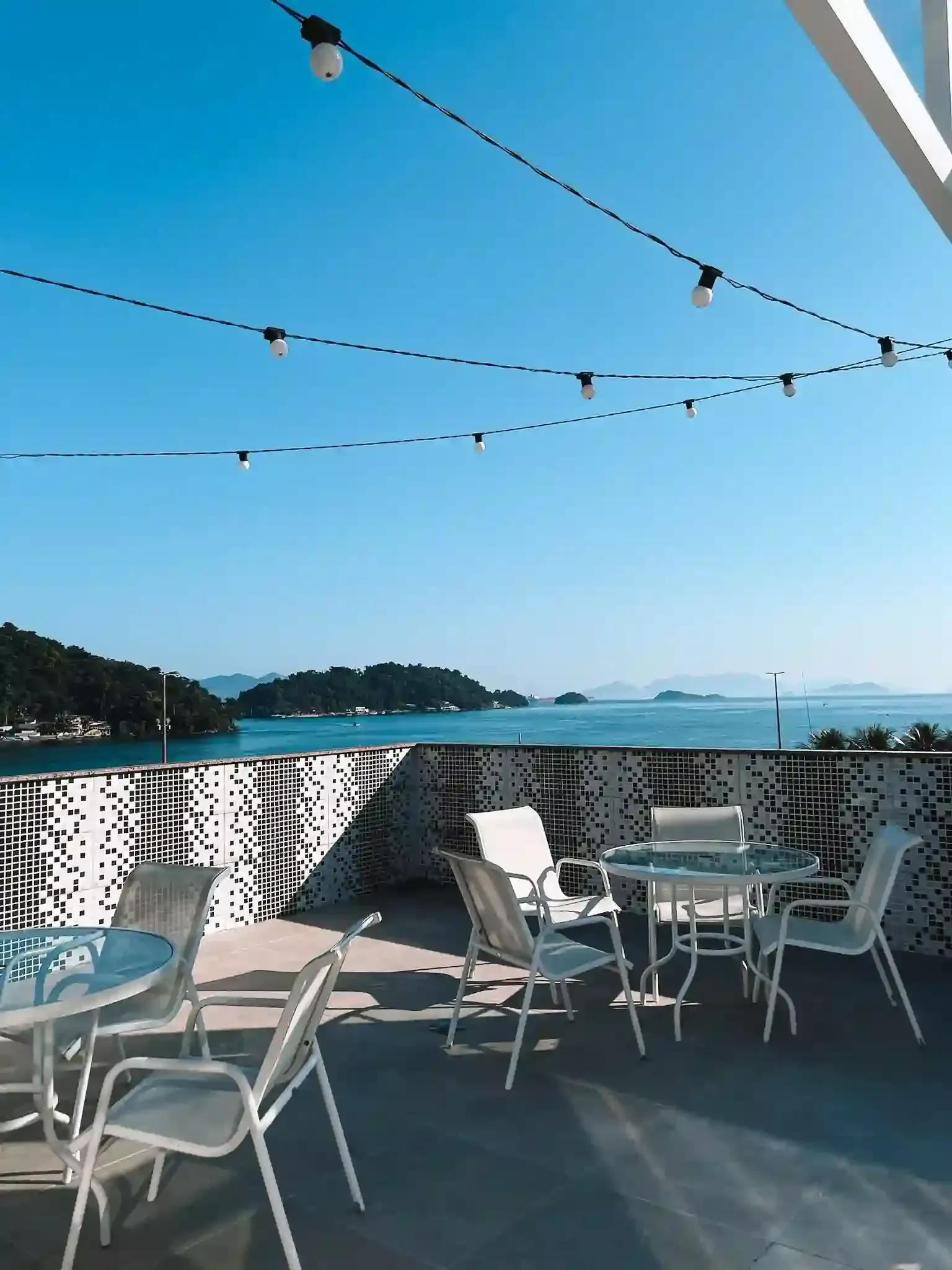 Uma varanda com mesas e cadeiras com vista para o oceano.-pousada-itacuruca-inn