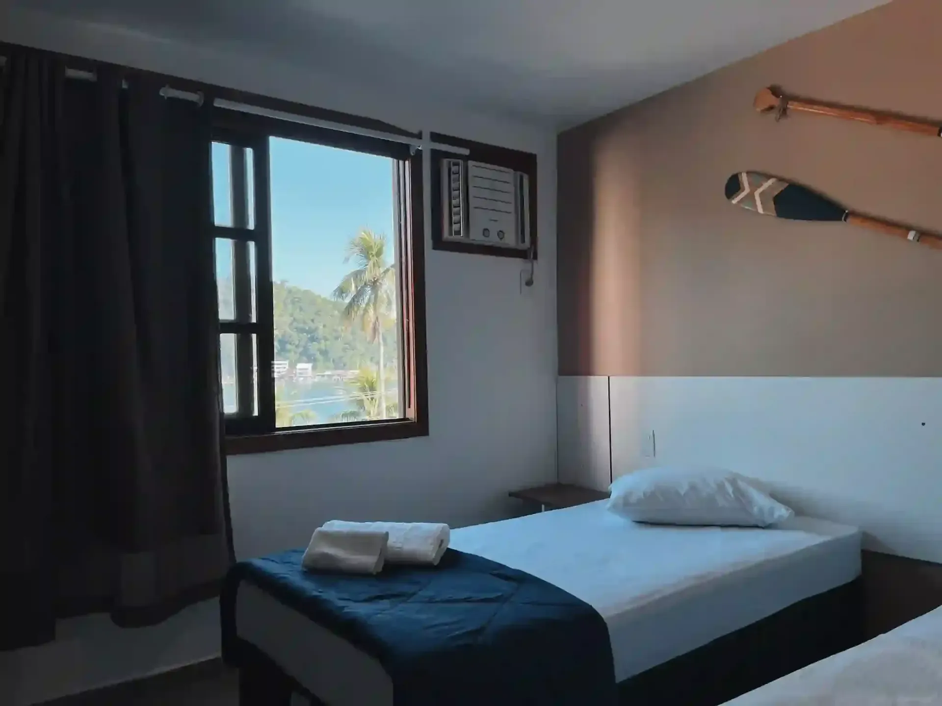 Um quarto com duas camas e uma janela com remos na parede.-pousada-itacuruca-inn