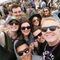 A group of people wearing sunglasses are posing for a picture at a festival.