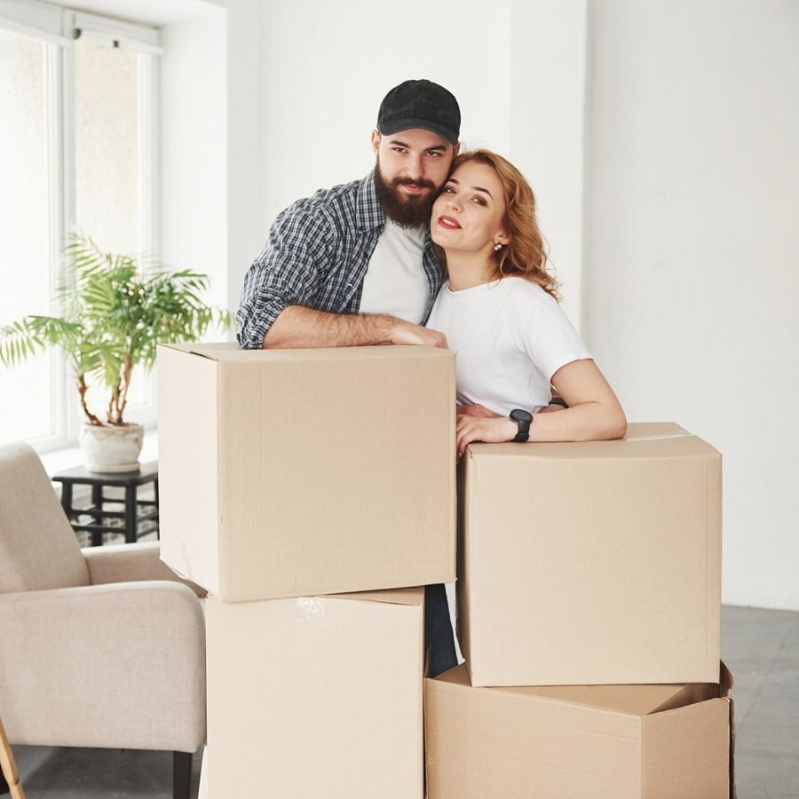 A man and a woman are standing next to a pile of cardboard boxes.