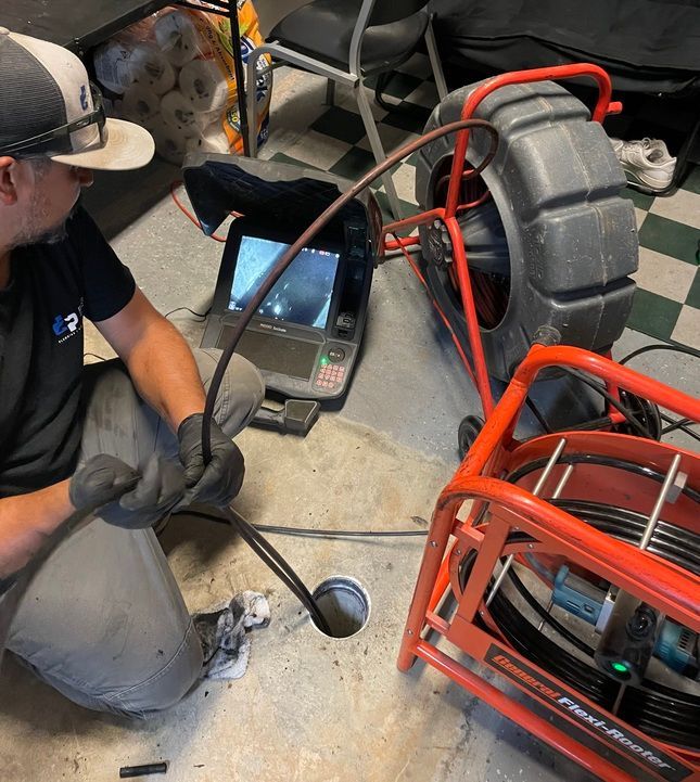 Plumber using camera equipment to inspect a drain in a concrete floor.