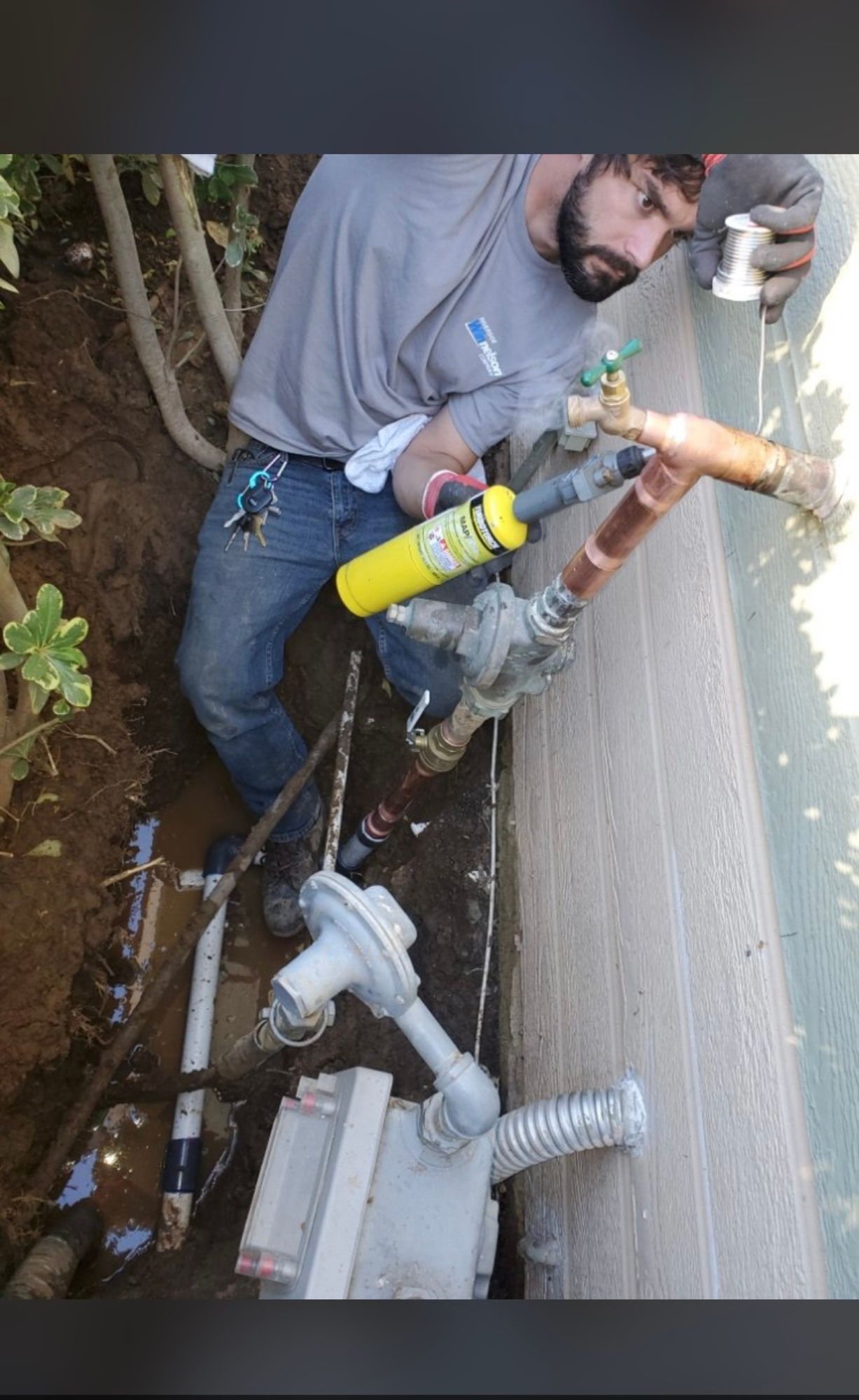 a man is working on a gas meter in the ground .