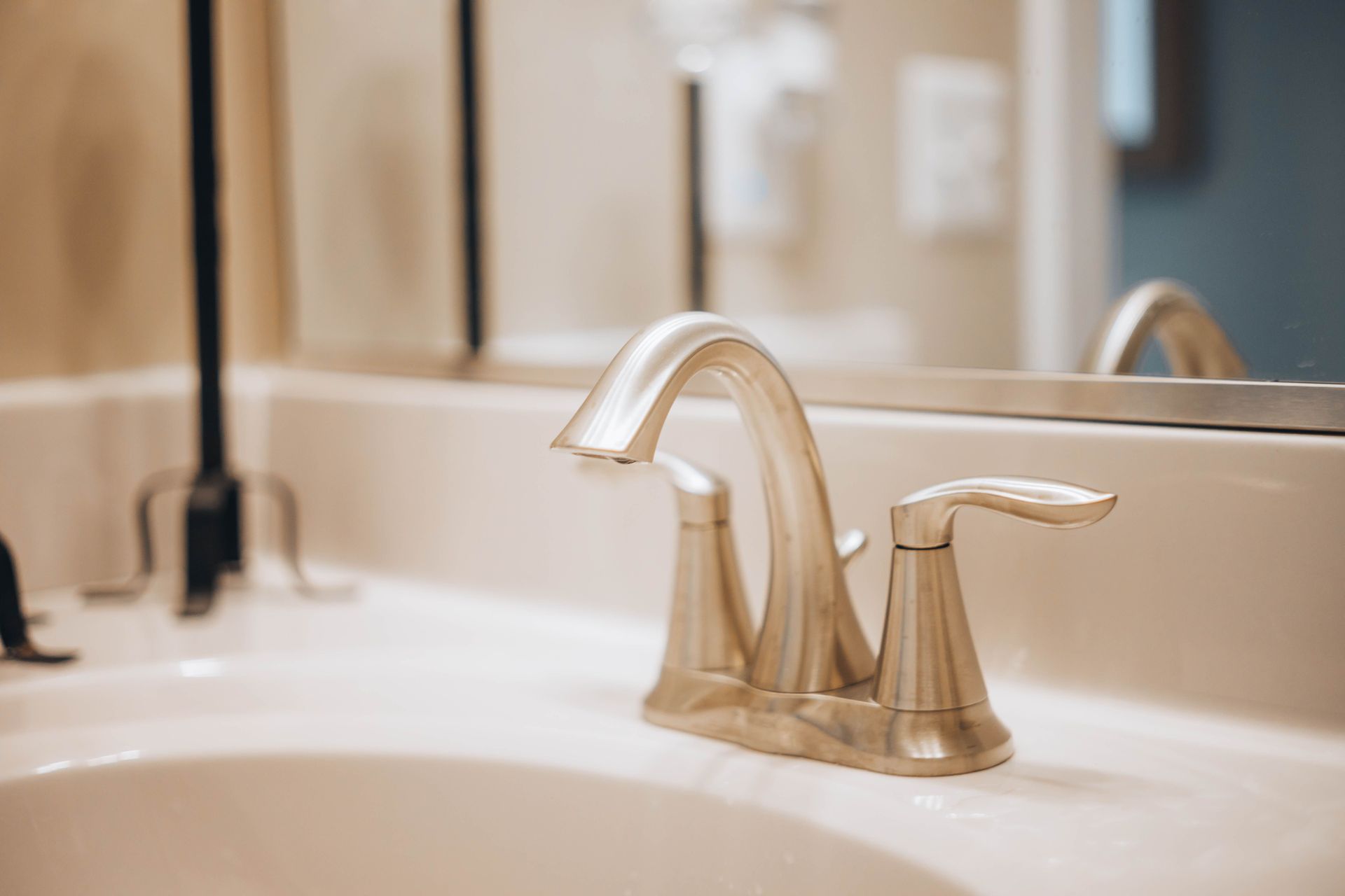 Bathroom sink with chrome faucet and mirror reflection on a beige countertop