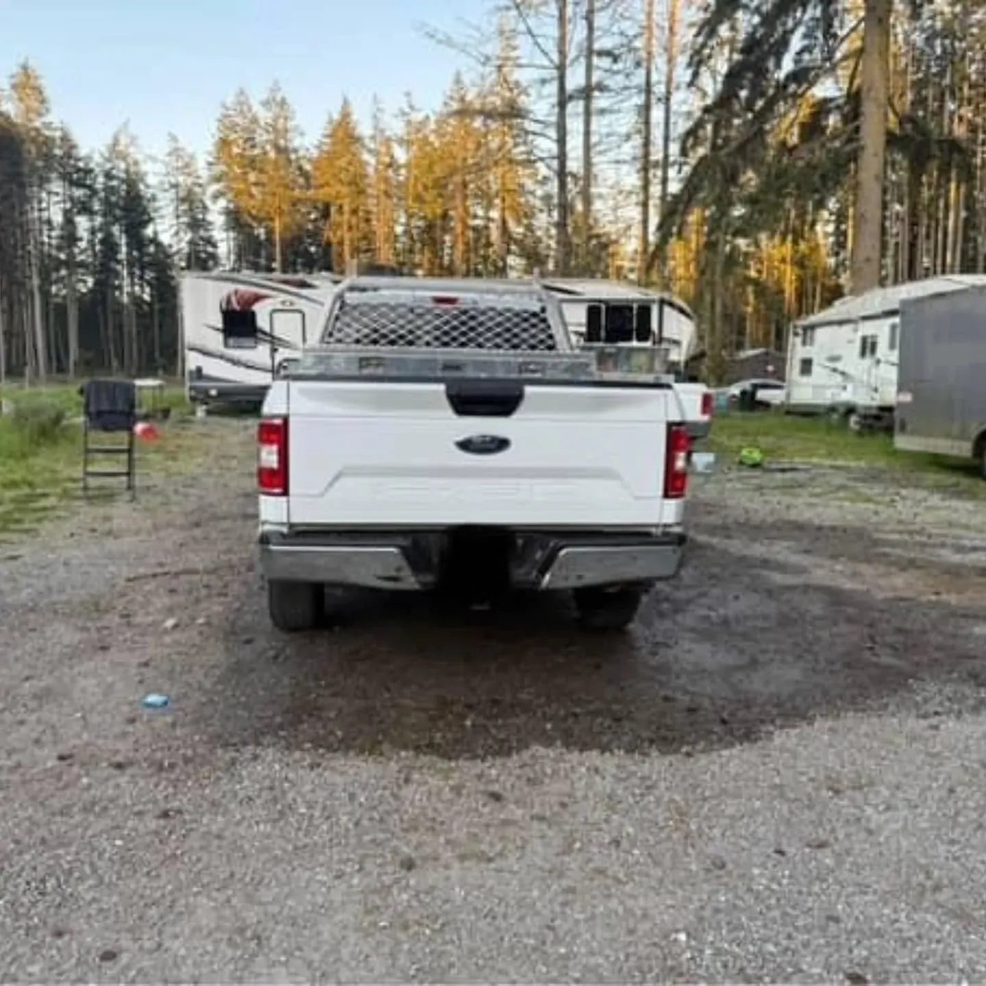 Woman in straw hat smiles, holding wine glass near a lake.
