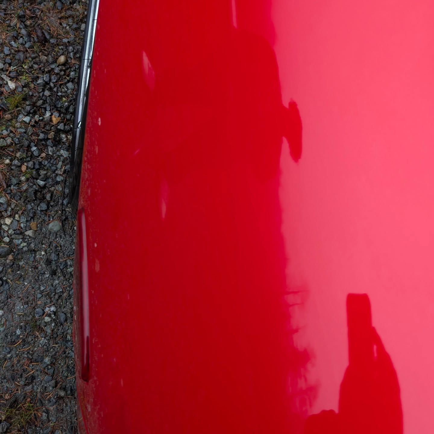 Woman in straw hat smiles, holding wine glass near a lake.