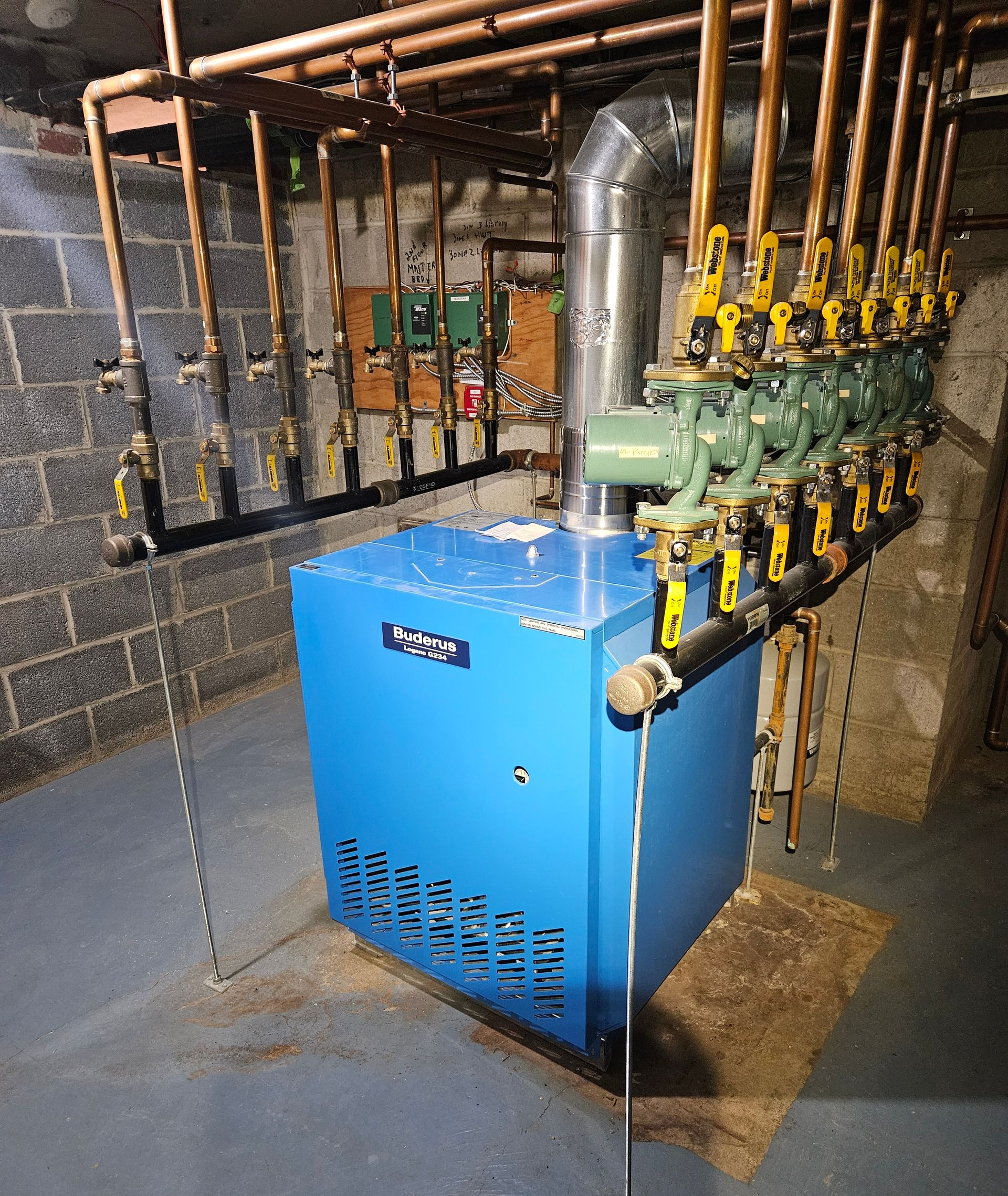 Blue boiler with copper pipes in a basement.