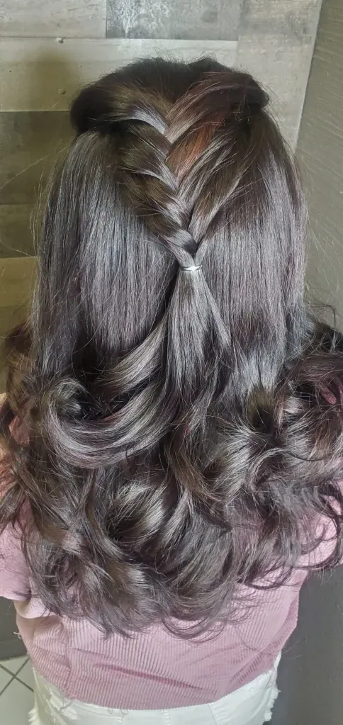 A woman with long hair is wearing a braided hairstyle.